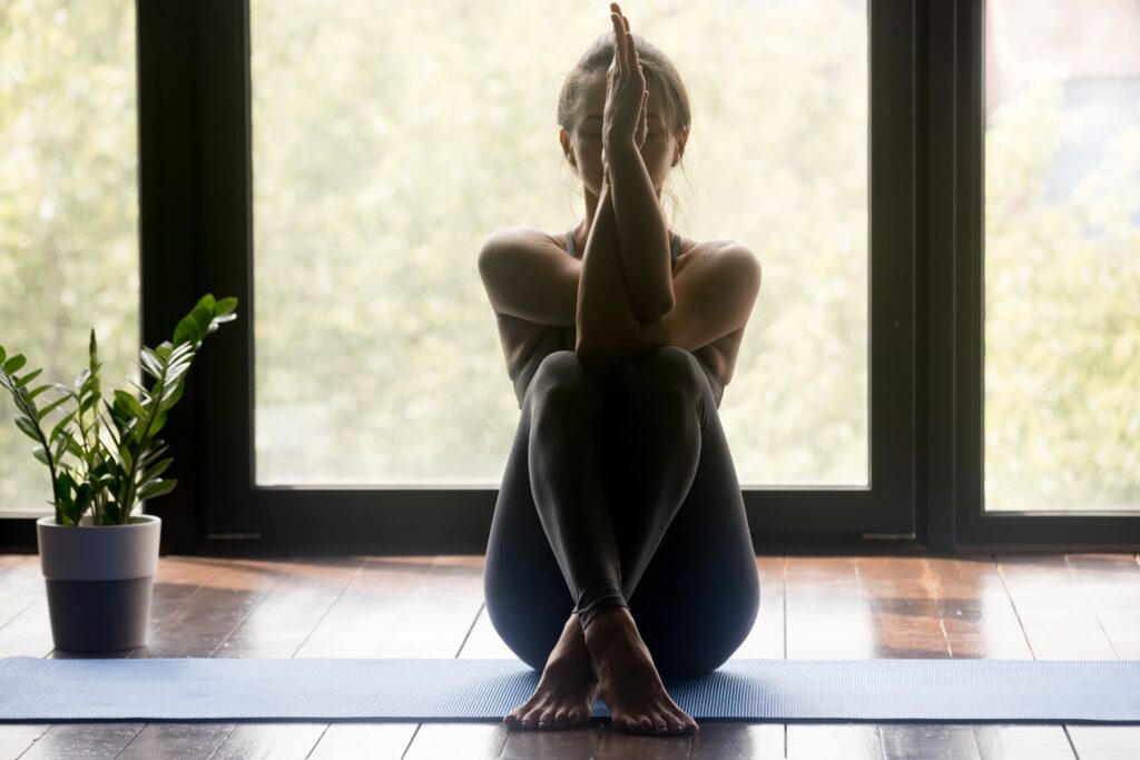A woman doing yoga in front of a window.