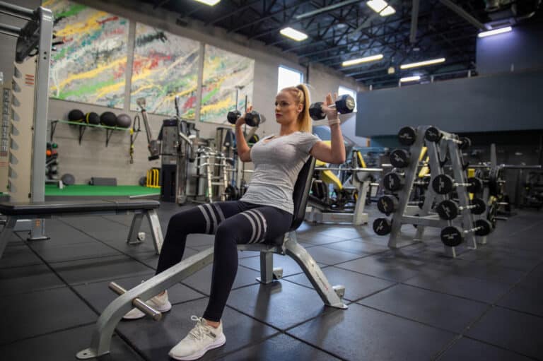 A woman lifting dumbbells in a gym.