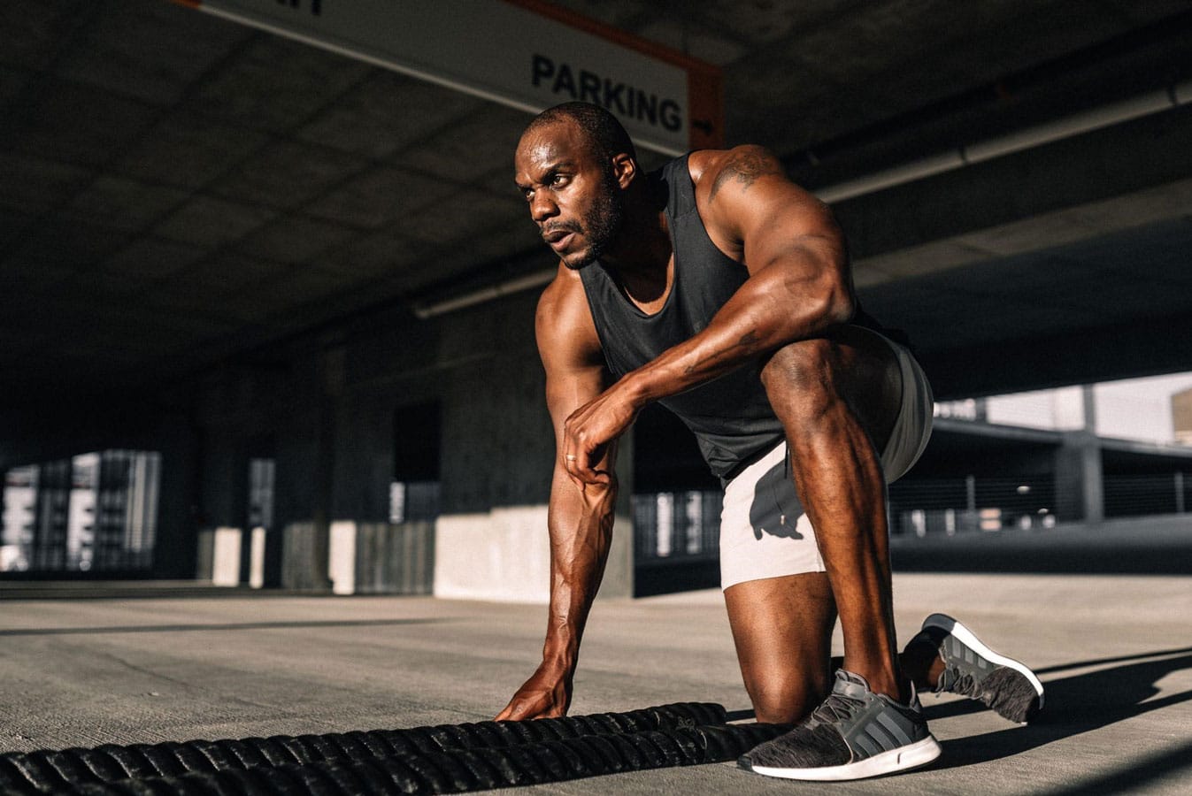 A man is stretching on a mat in a parking lot.