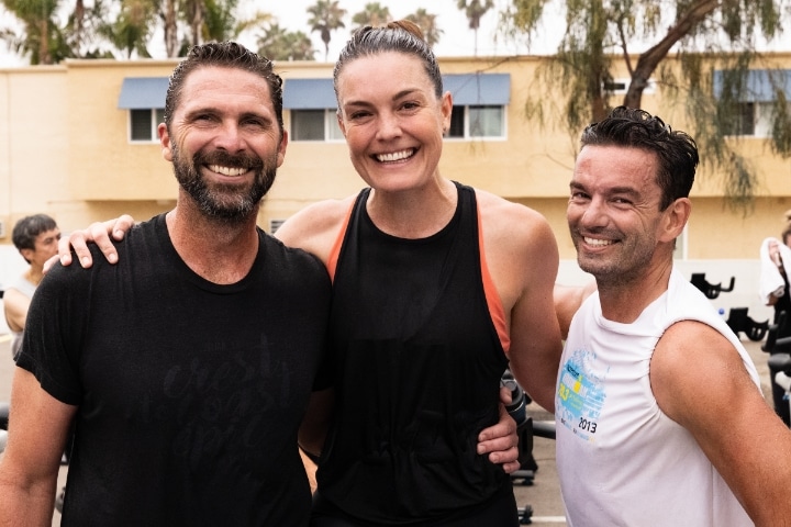 Two men with woman in middle after a workout