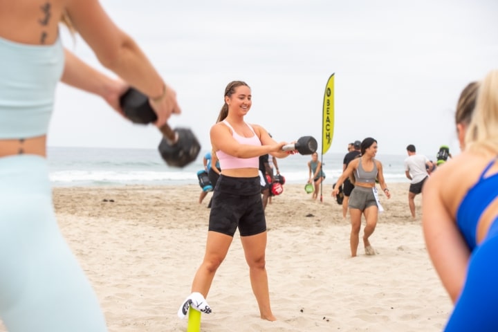 Three girls wearing colorful workout clothes working out on the sand