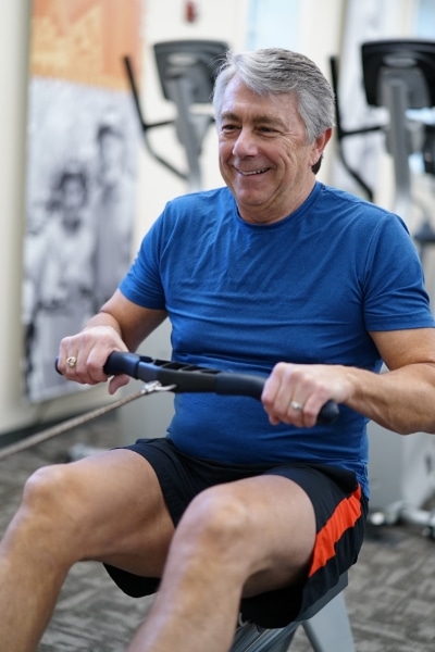 An older man on a rowing machine in a gym.