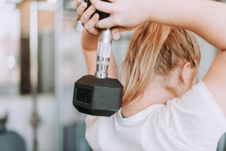 woman lifting dumbbell behind back at fit athletic club