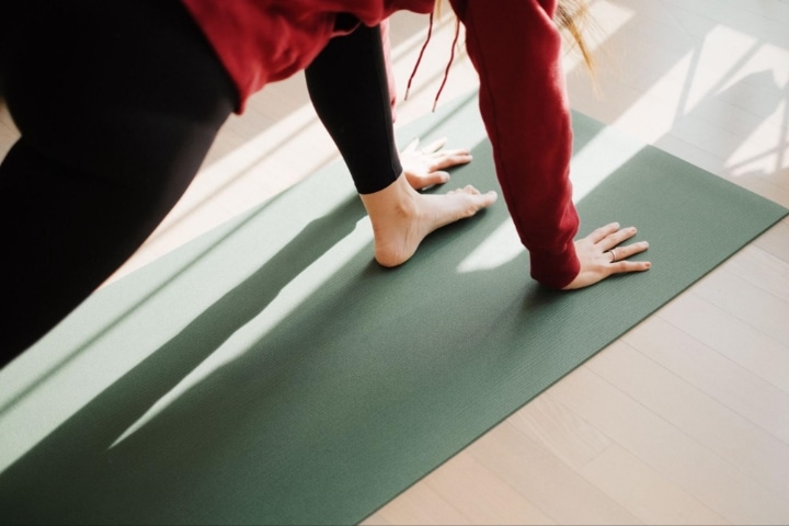 A woman doing yoga on a green mat.