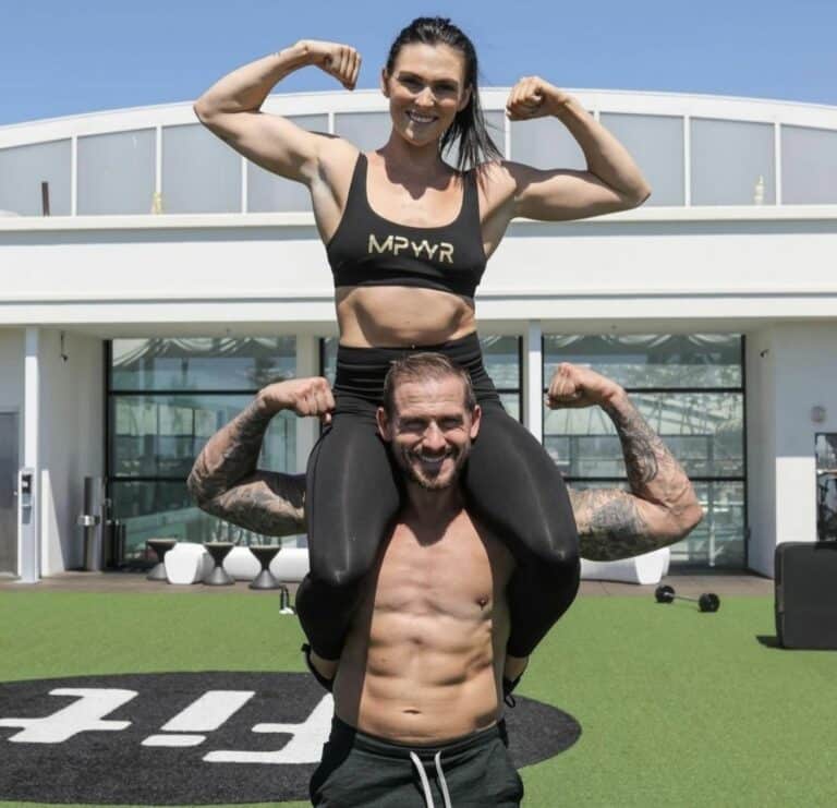A man and woman posing for a photo in front of a gym.