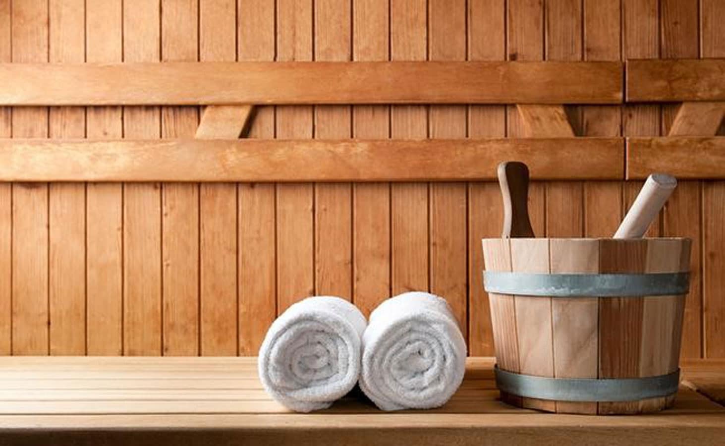 Two towels and a bucket in a wooden sauna.