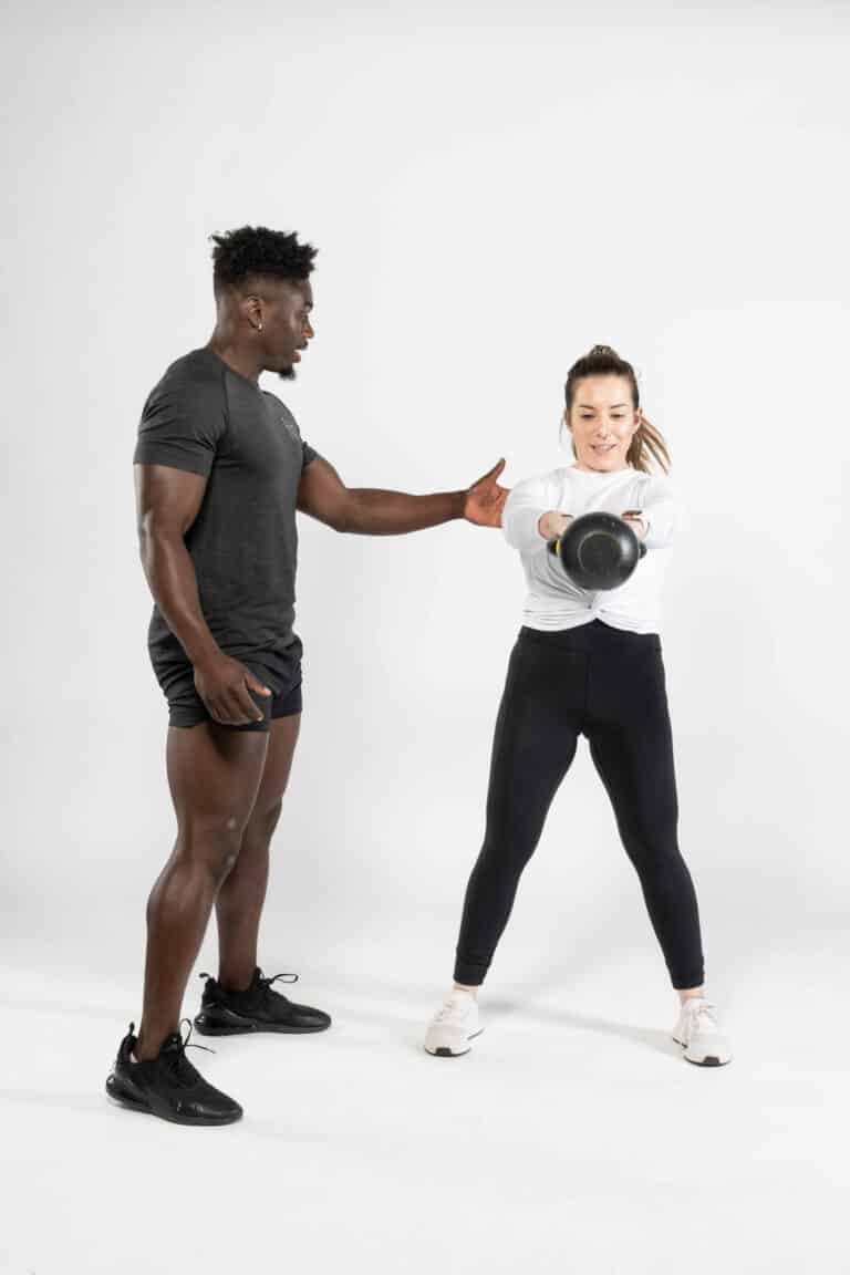 A man and a woman doing a kettlebell exercise.