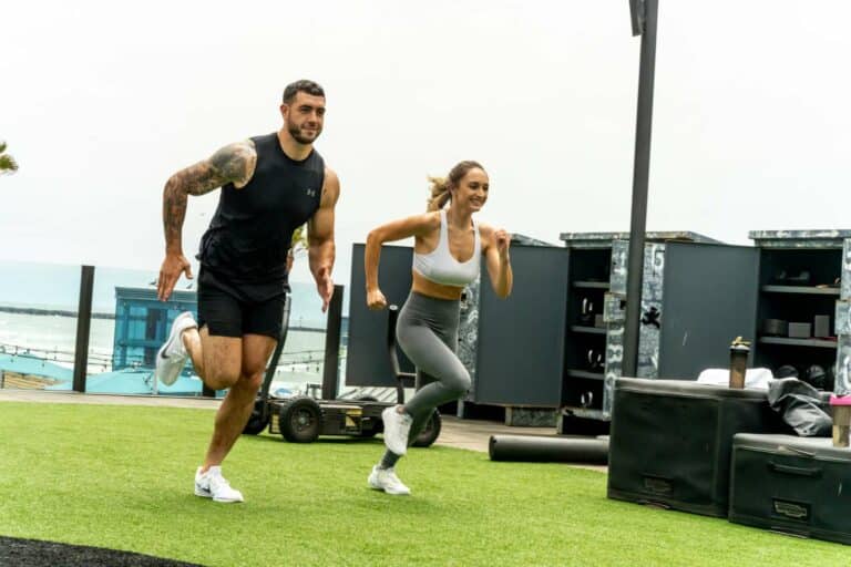 A man and woman running in a gym.