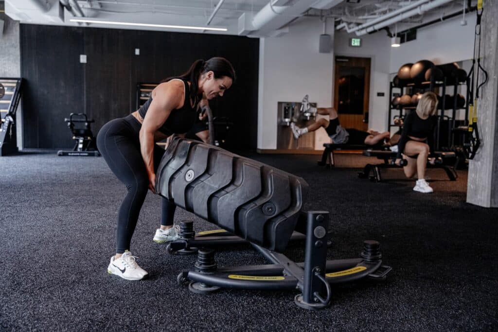 A woman lifting a large weight in a gym.