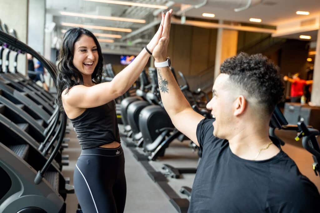 A man and woman giving each other high fives in a gym.
