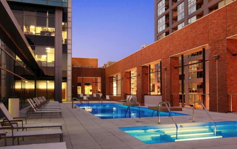 A swimming pool in front of a building at dusk.