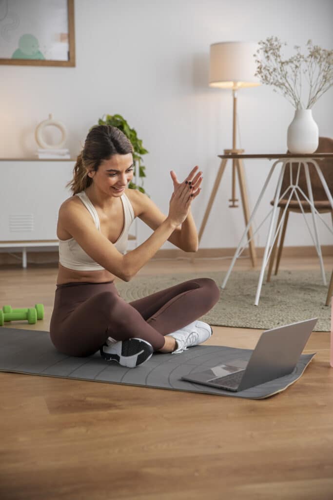 A woman sitting on a yoga mat and clapping her hands.