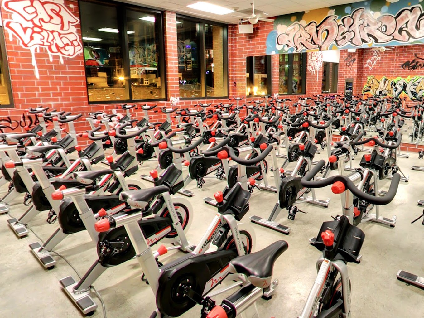 Spinning bikes in a gym with graffiti on the walls.