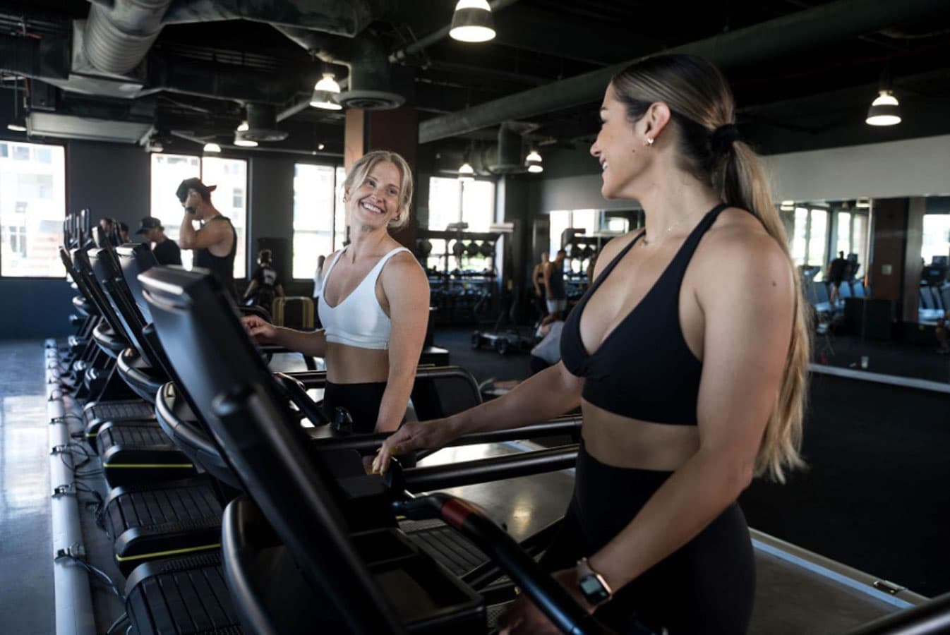 Two women on treadmills in a gym.