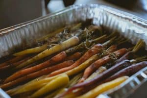 Colorful roasted carrots in a silver tray, seasoned and arranged in rows.