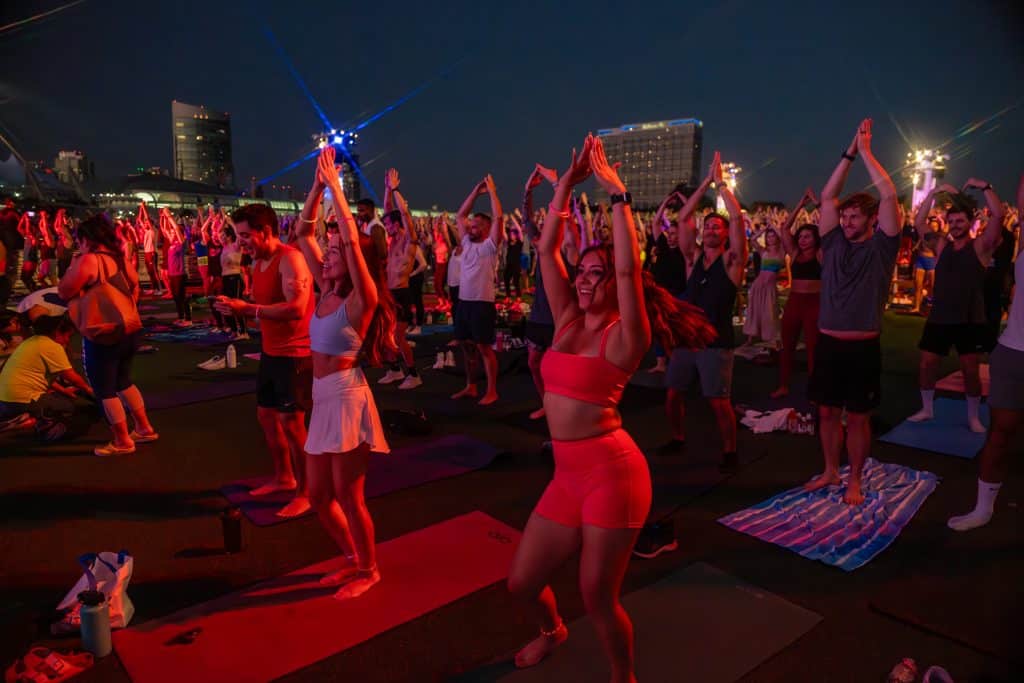 The open -air crowd practiced on the mats at night, with a horizon in the background. Many participants raised their arms.